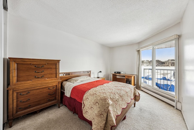 bedroom featuring a textured ceiling, light colored carpet, and a baseboard heating unit