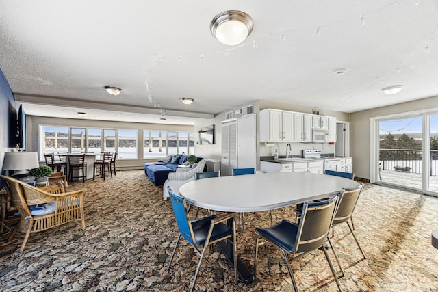 dining room featuring sink, carpet, a textured ceiling, and a wealth of natural light