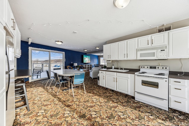 kitchen with white appliances, white cabinets, a textured ceiling, and sink