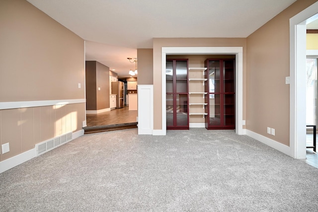 carpeted spare room with a notable chandelier