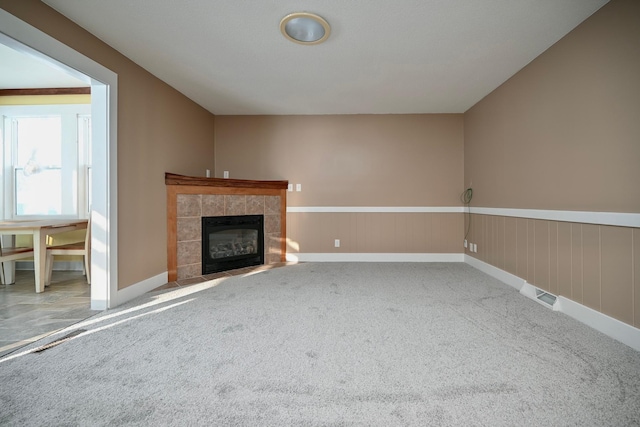 unfurnished living room with carpet flooring, wood walls, and a fireplace