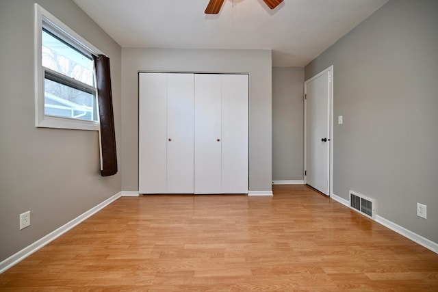 unfurnished bedroom with ceiling fan, light wood-type flooring, and a closet