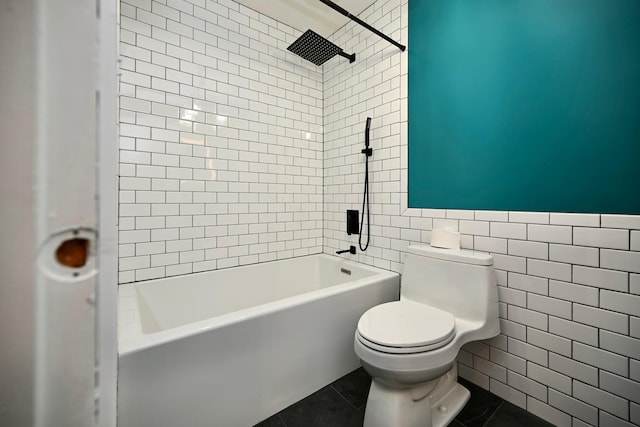 bathroom with tile patterned floors, tiled shower / bath combo, toilet, and tile walls