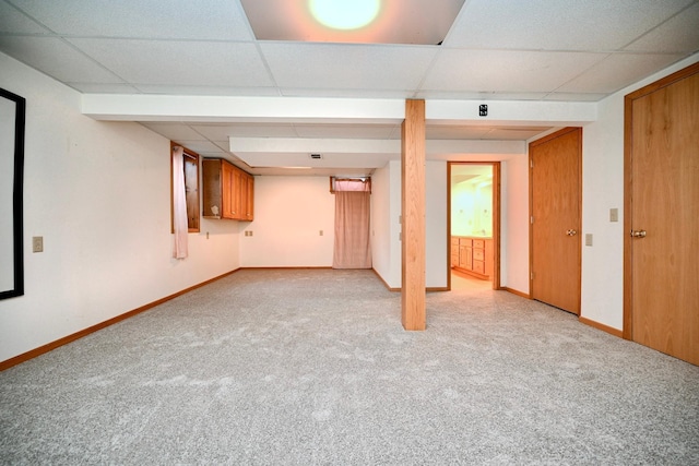 basement featuring a paneled ceiling and light colored carpet