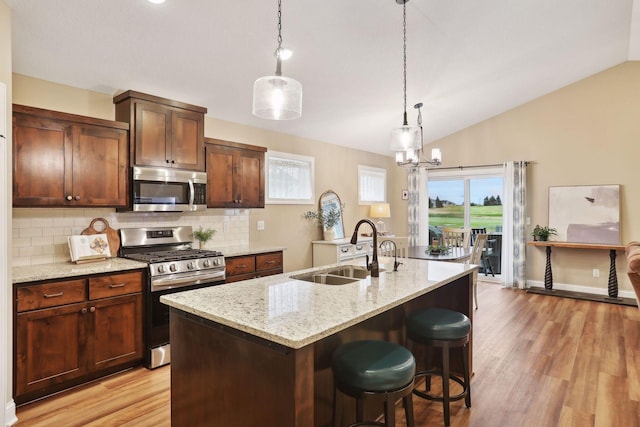 kitchen featuring backsplash, a center island with sink, sink, vaulted ceiling, and stainless steel appliances