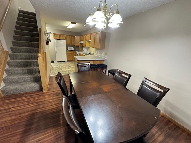 dining room with hardwood / wood-style floors, a textured ceiling, and a notable chandelier