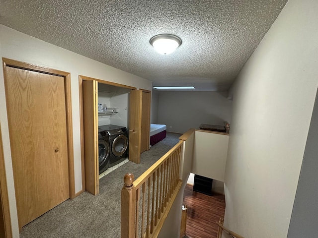 corridor with a textured ceiling, washing machine and dryer, and dark carpet