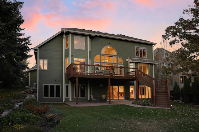 back of property at dusk with a patio area, a wooden deck, stairs, and a yard