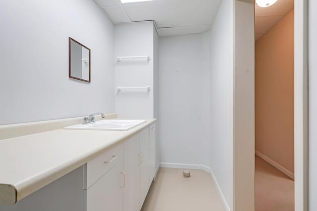 bathroom featuring baseboards, a drop ceiling, and vanity