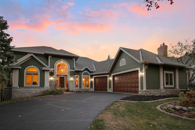 view of front of house with aphalt driveway, roof with shingles, a chimney, a garage, and stone siding