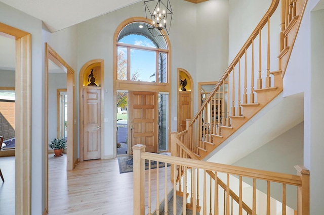 entrance foyer with a towering ceiling, an inviting chandelier, and wood finished floors