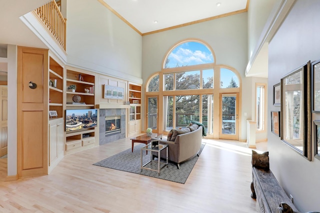 living room with ornamental molding, a tile fireplace, and light wood-style flooring