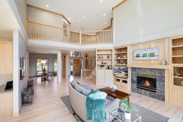 living area with ornamental molding, stairway, wood finished floors, and a tile fireplace