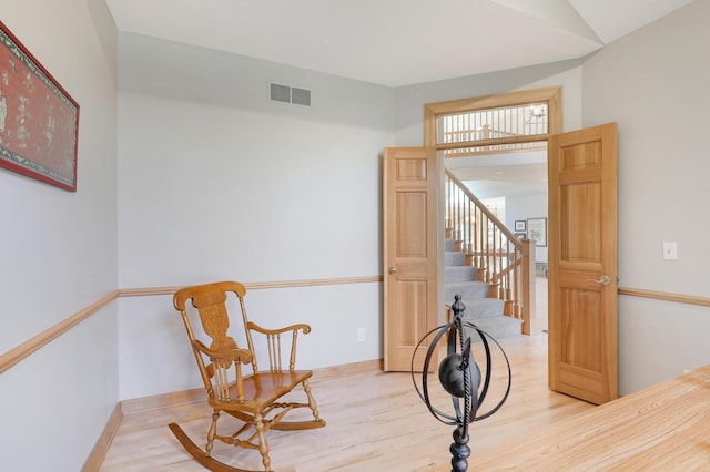 sitting room with stairway, wood finished floors, visible vents, and baseboards