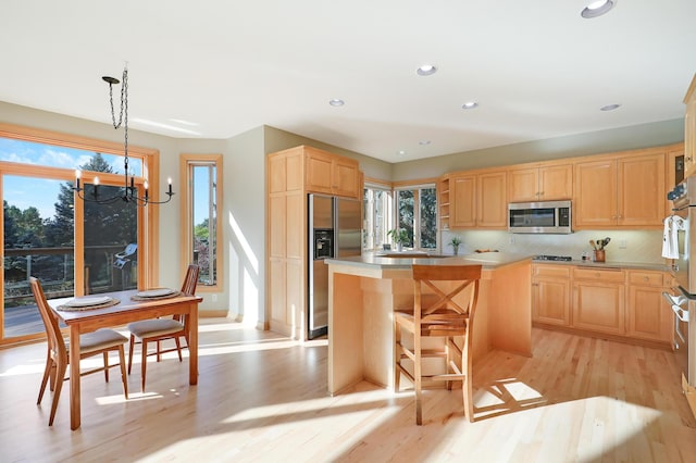 kitchen featuring stainless steel microwave, light wood-style flooring, light brown cabinets, a kitchen island, and built in refrigerator