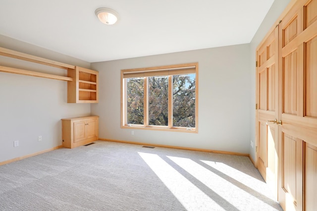 unfurnished bedroom with baseboards, visible vents, and light colored carpet