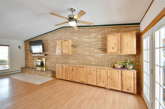 kitchen featuring light brown cabinets, lofted ceiling, and brick wall