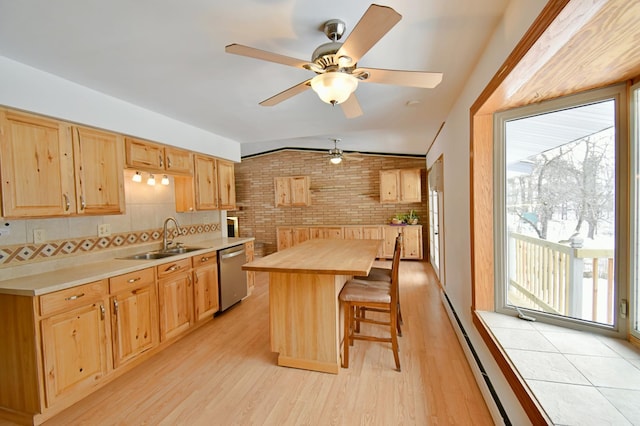 kitchen featuring dishwasher, a center island, sink, brick wall, and vaulted ceiling