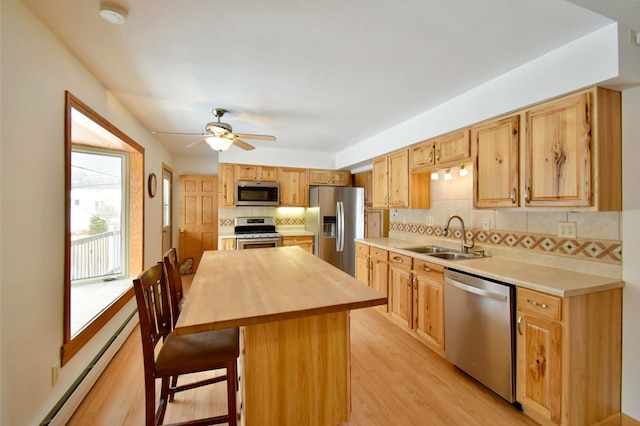 kitchen featuring decorative backsplash, a kitchen bar, stainless steel appliances, sink, and a kitchen island