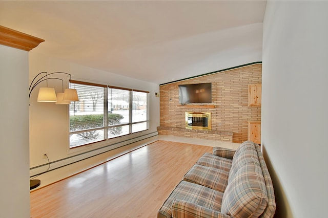 living room featuring baseboard heating, light hardwood / wood-style flooring, vaulted ceiling, and a brick fireplace