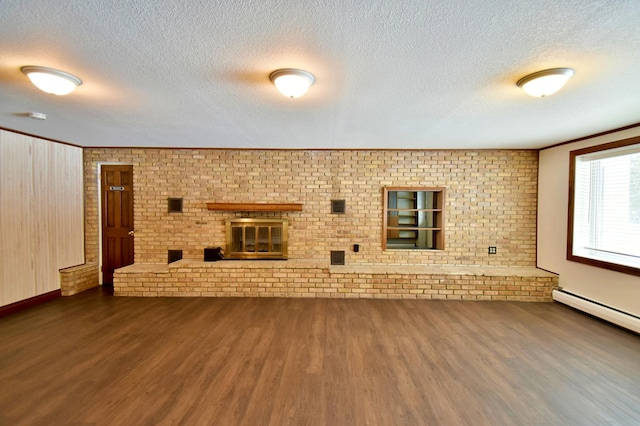 unfurnished living room featuring dark hardwood / wood-style floors, baseboard heating, a textured ceiling, and brick wall