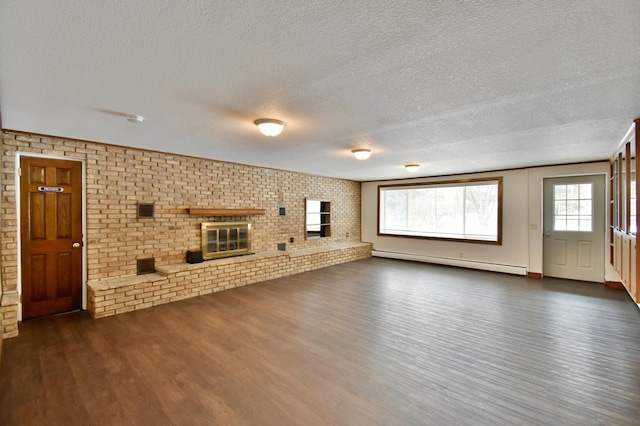 unfurnished living room featuring dark wood-type flooring, a brick fireplace, a textured ceiling, baseboard heating, and brick wall