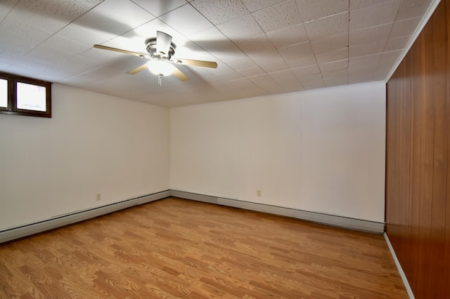 basement featuring ceiling fan, wood walls, and light hardwood / wood-style flooring