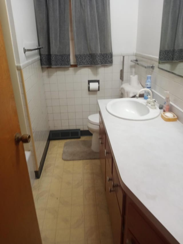 bathroom featuring tile patterned flooring, vanity, toilet, and tile walls