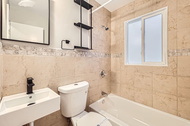 full bathroom with tile walls, sink, tiled shower / bath combo, and toilet