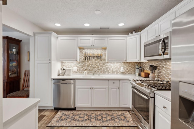 kitchen with light wood-type flooring, appliances with stainless steel finishes, white cabinetry, and sink