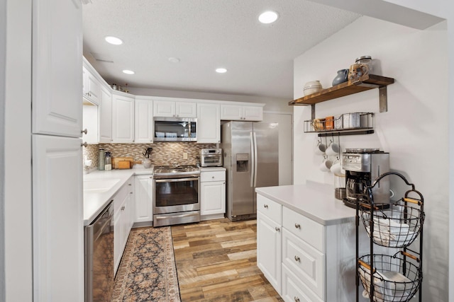 kitchen featuring white cabinetry, light hardwood / wood-style floors, appliances with stainless steel finishes, backsplash, and a textured ceiling