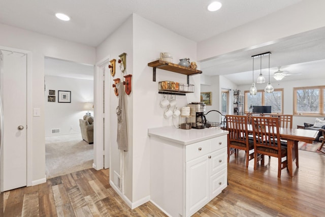 kitchen featuring ceiling fan, white cabinetry, light hardwood / wood-style flooring, and hanging light fixtures