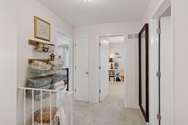 hallway featuring light carpet and a textured ceiling