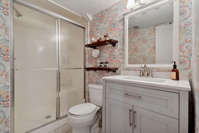 bathroom with toilet, vanity, a shower with door, and a textured ceiling