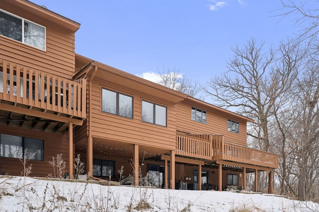 snow covered rear of property featuring a wooden deck