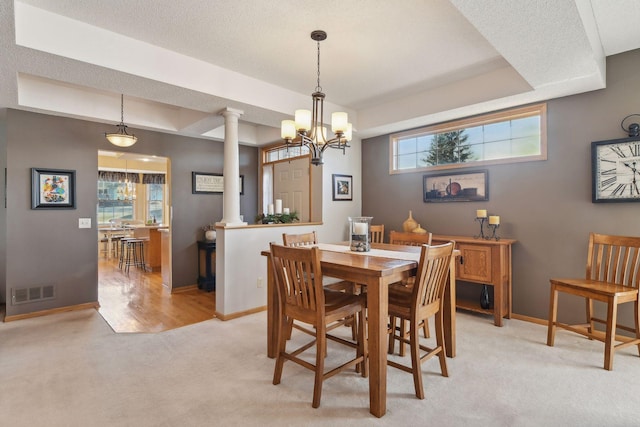 dining area with decorative columns, light carpet, and a chandelier