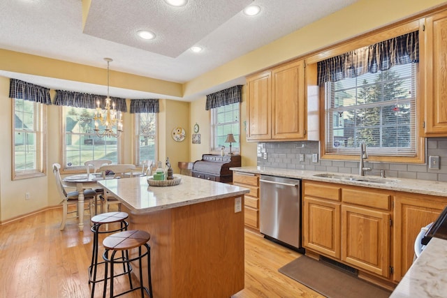 kitchen featuring a kitchen island, pendant lighting, tasteful backsplash, sink, and stainless steel dishwasher