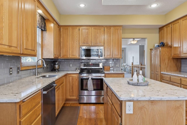 kitchen with stainless steel appliances, sink, backsplash, and light hardwood / wood-style floors