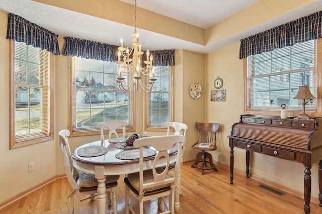 dining room with wood-type flooring, plenty of natural light, and a notable chandelier