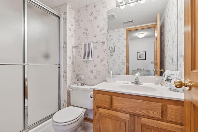 bathroom featuring vanity, a shower with door, toilet, and a textured ceiling