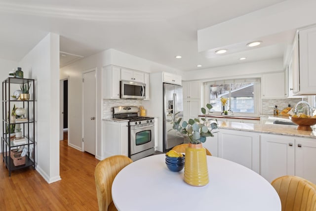 kitchen with white cabinets, light stone countertops, sink, and appliances with stainless steel finishes