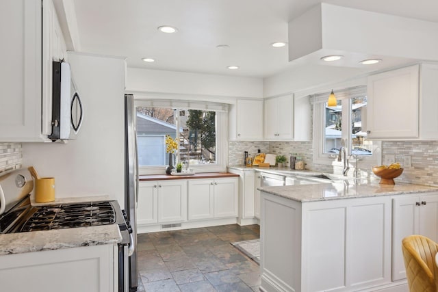 kitchen with light stone countertops, a healthy amount of sunlight, sink, white range with gas stovetop, and white cabinetry