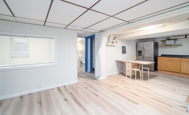 interior space featuring a paneled ceiling, stainless steel fridge with ice dispenser, and light hardwood / wood-style flooring