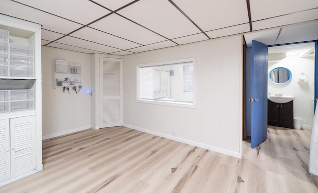 spare room with a paneled ceiling, light hardwood / wood-style floors, and sink