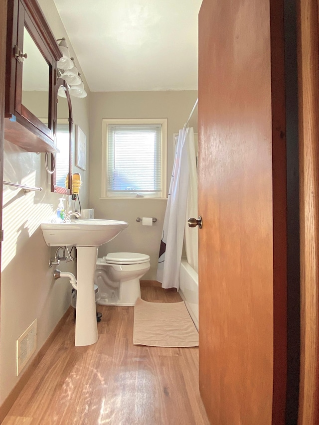 bathroom with toilet, shower / bath combo, and hardwood / wood-style flooring