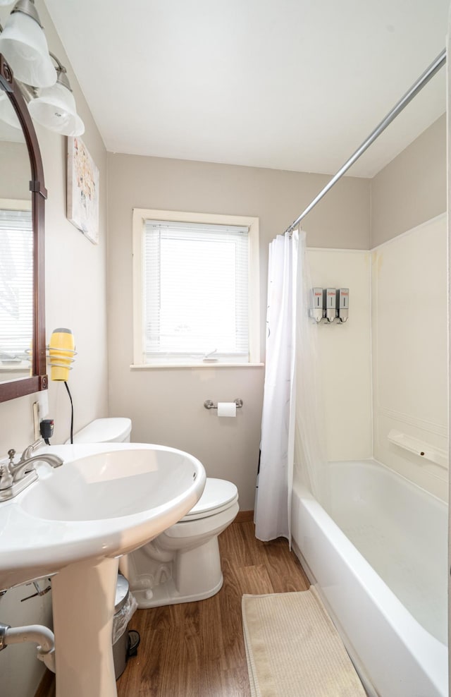 bathroom with shower / bath combo with shower curtain, wood-type flooring, toilet, and a healthy amount of sunlight