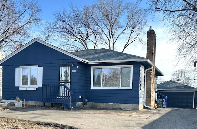 view of front of home with a garage, an outbuilding, and a chimney