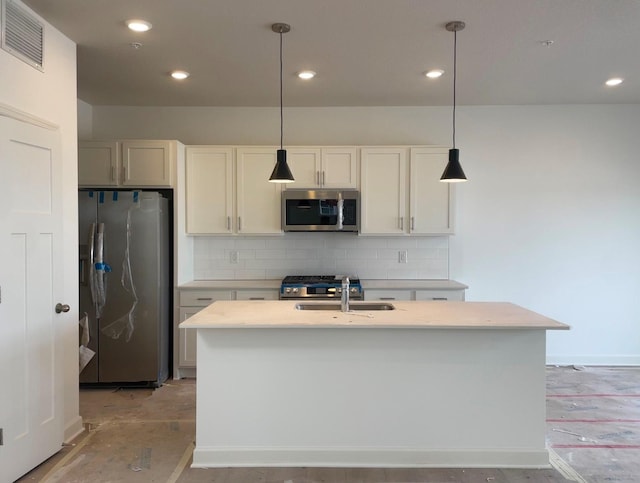 kitchen featuring pendant lighting, appliances with stainless steel finishes, tasteful backsplash, an island with sink, and sink