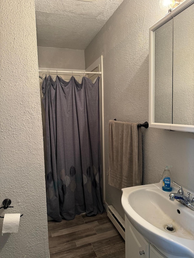 bathroom with baseboard heating, a shower with curtain, a textured ceiling, vanity, and hardwood / wood-style flooring