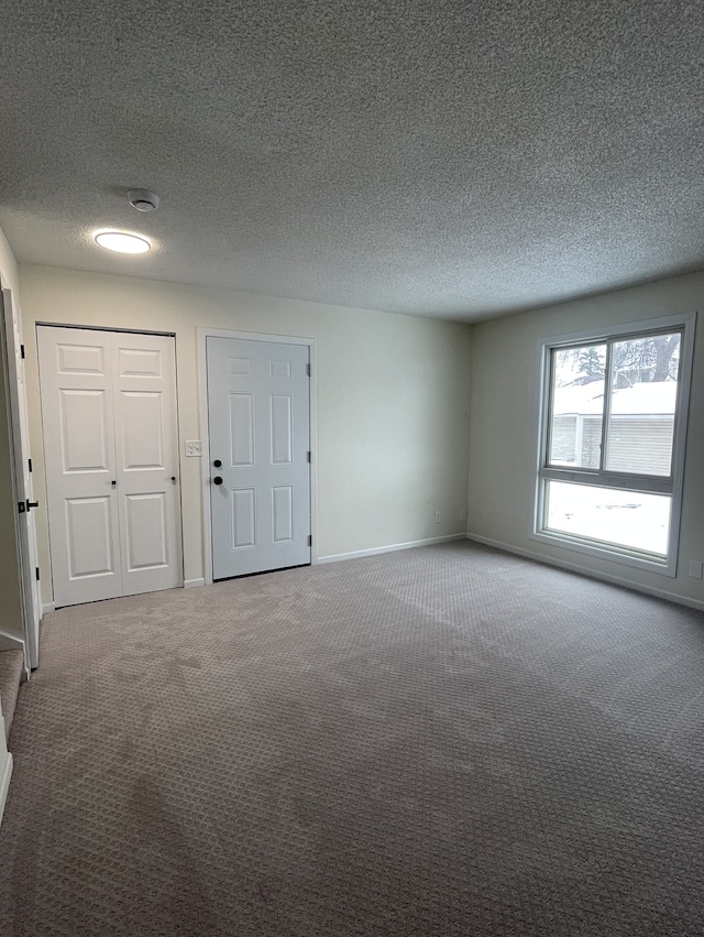 carpeted empty room featuring a textured ceiling